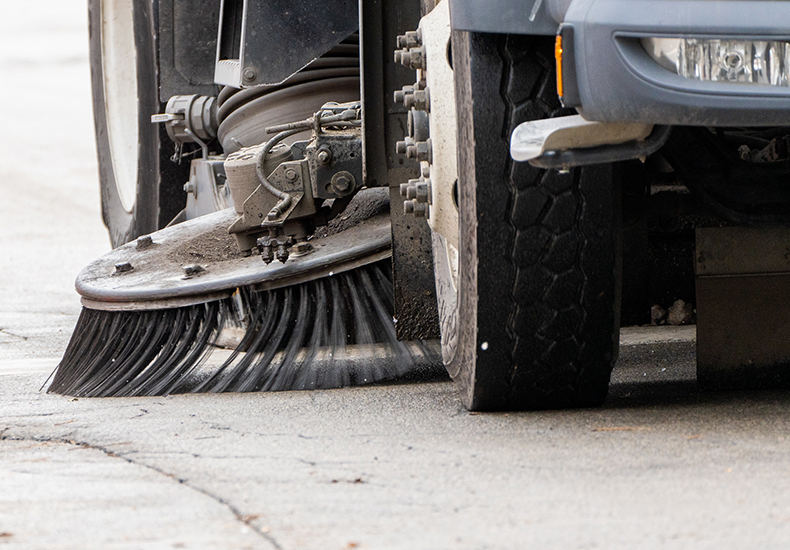 Close up of the street sweeping mechanism on a street sweeping vehicle.