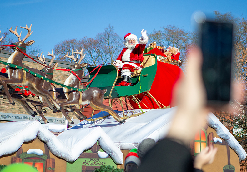 A hand holding a mobile phone snaps a photo of Santa during the Oakville Santa Claus Parade.