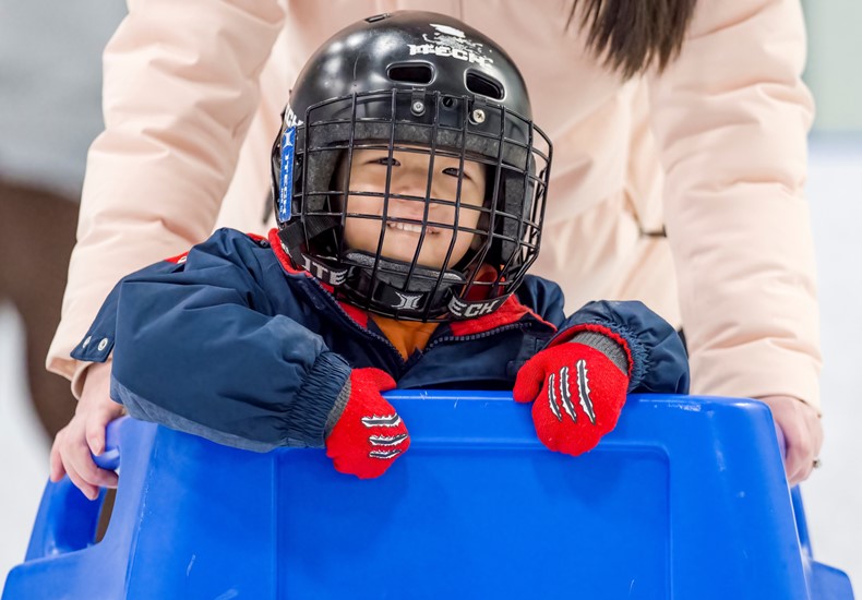 Young child ice skating with a skating aid